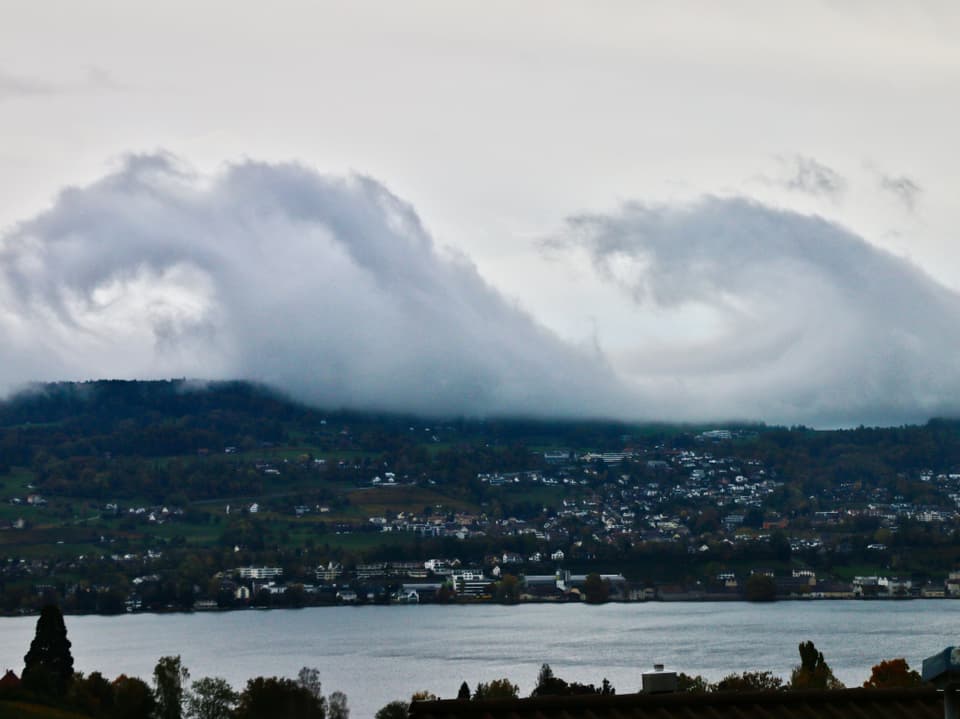 Wolken werden vom Wind zu Wellen geformt, im Vordergund der Zürichsee.