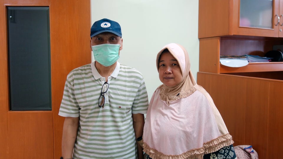 Ein Mann mit Mundschutz steht neben einer Frau.