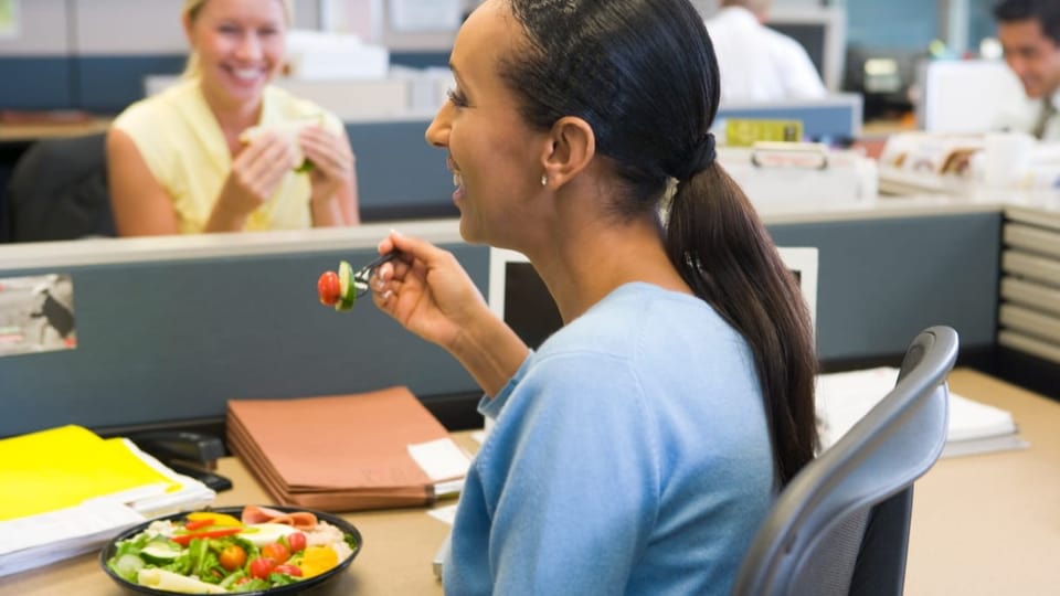 Eine Frau isst Salat am Arbeitsplatz.