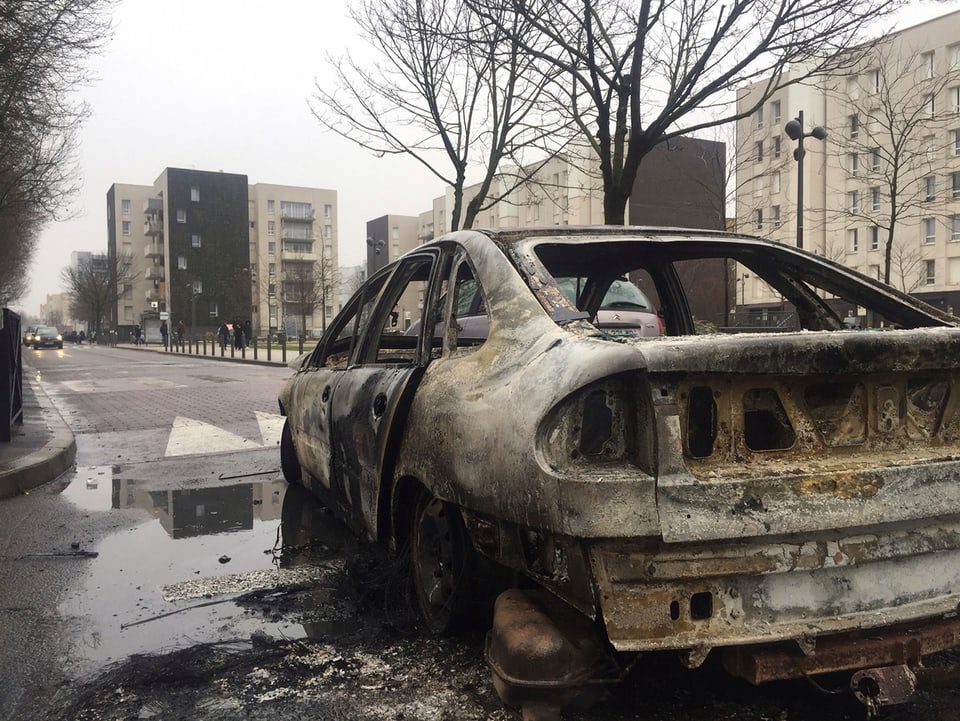 Ein ausgebranntes Auto vor der tristen Kulisse der Pariser Vorstadt Aulnay-sous-Bois.
