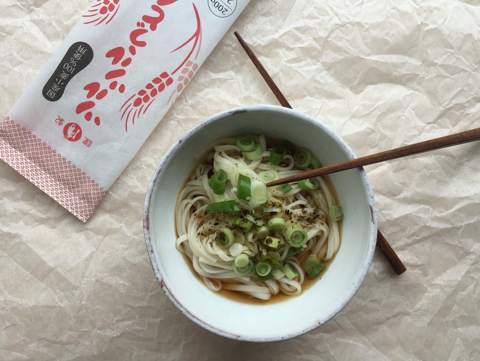 Schale mit Udon Nudeln in Brühe mit Frühlingszwiebel.