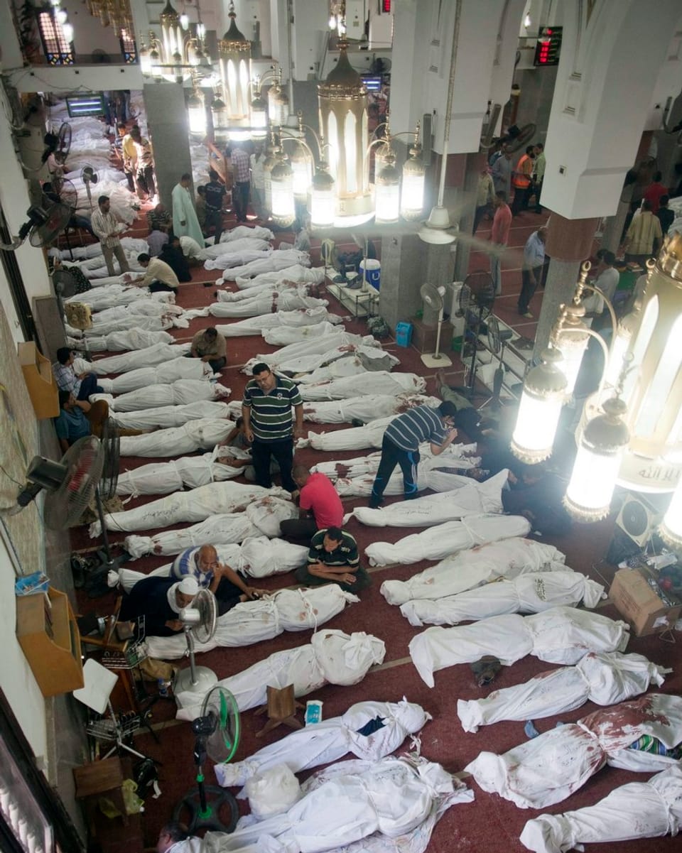 Leichen in weissen Tüchern reihen sich auf dem Boden einer Moschee.