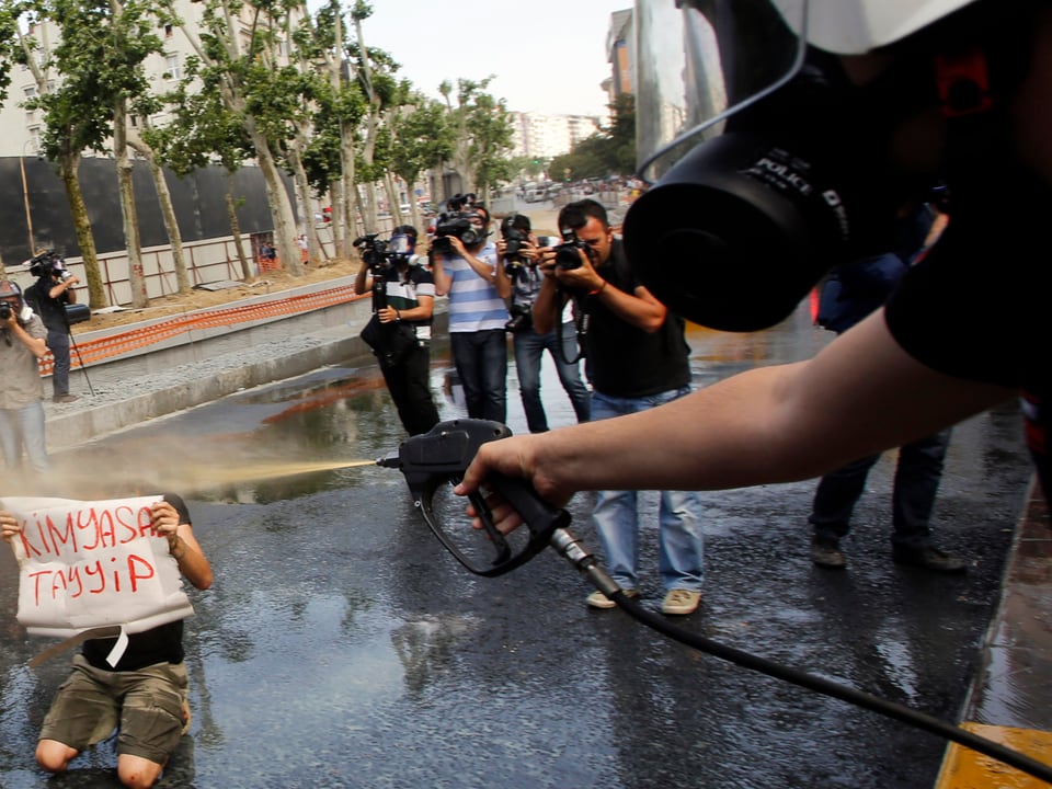 Ein Polizist sprüht Tränengas auf einen Demonstranten.