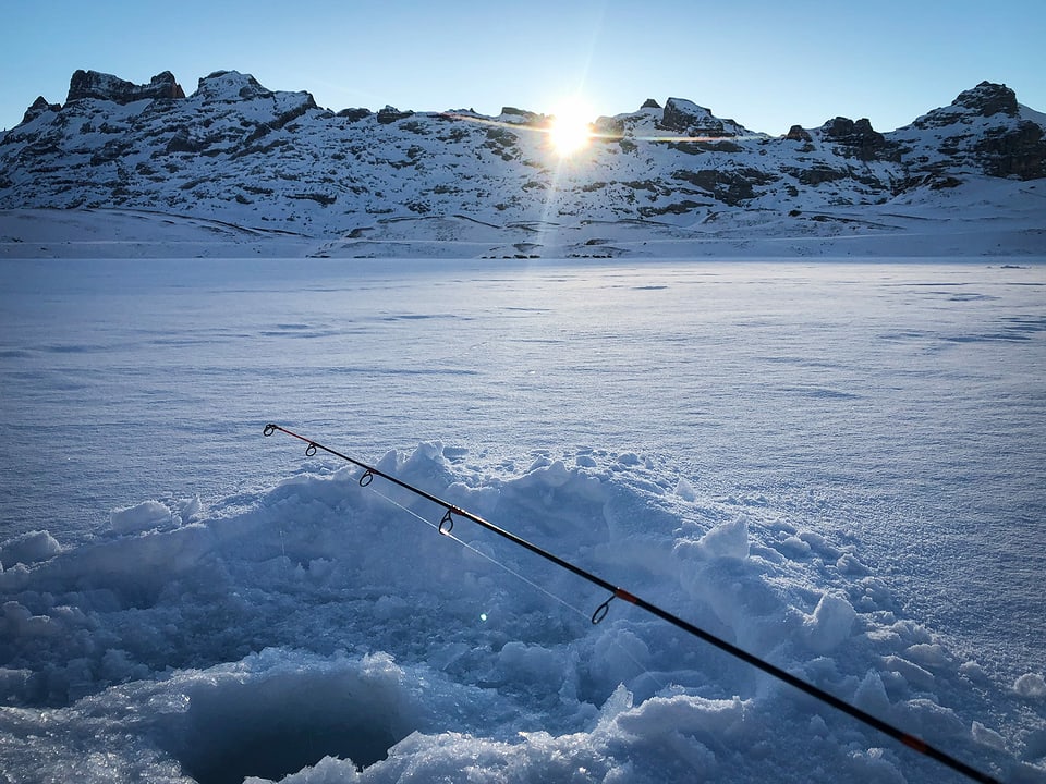 Fischerrute auf zugefrorenem Bergsee