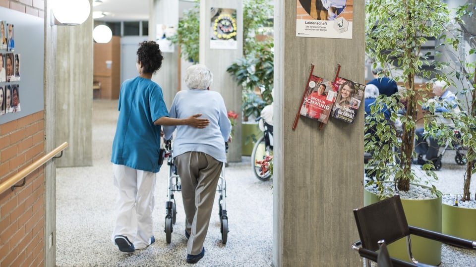 Pflegende hilft Frau am Rollator