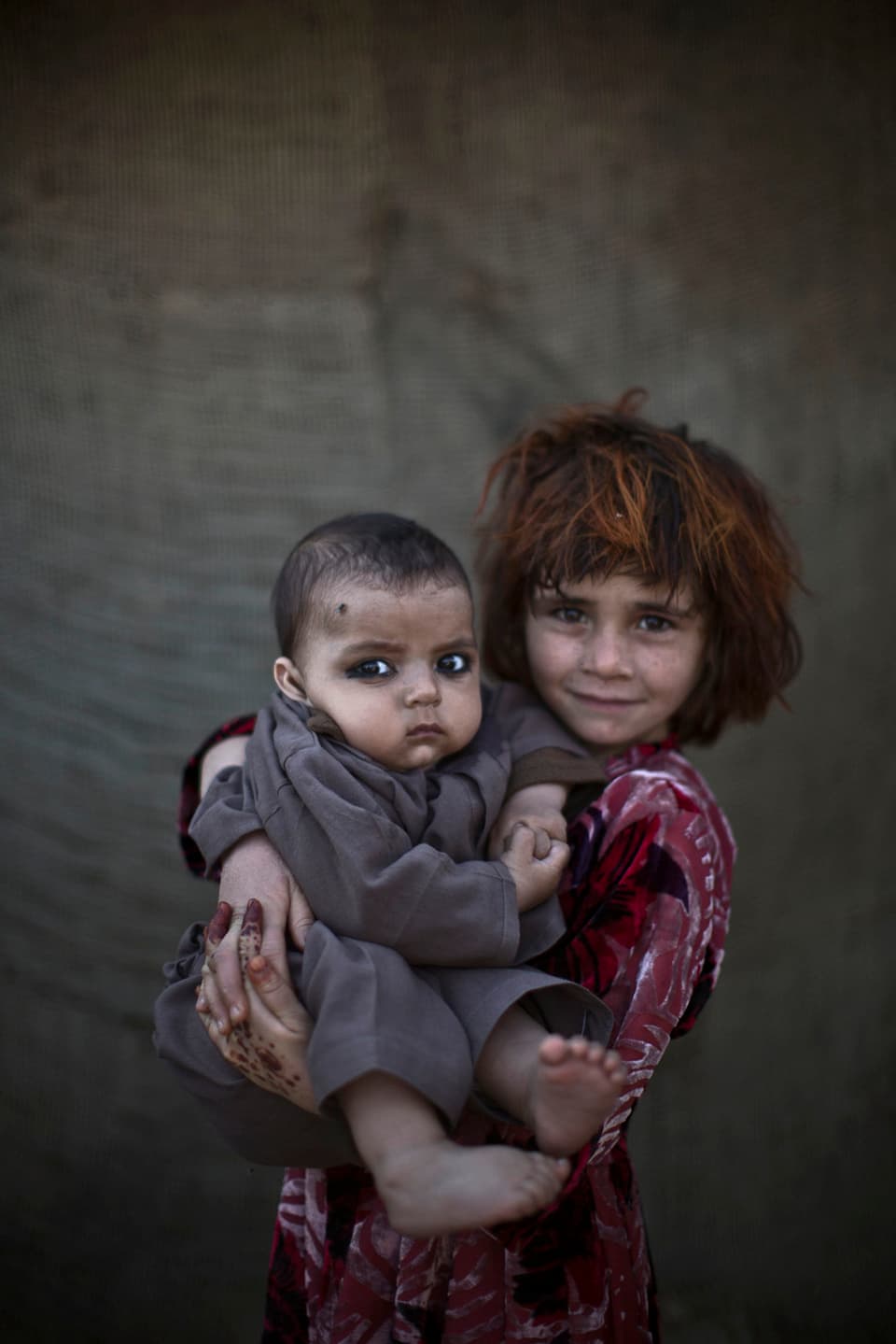 Afghanisches Flüchtlingsmädchen hält ihren Cousin im Arm