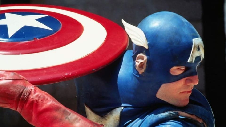 Filmausschnitt aus der 90er-Jahre-Adaption von Captain America: Der Titelheld holt zum Wurf aus.