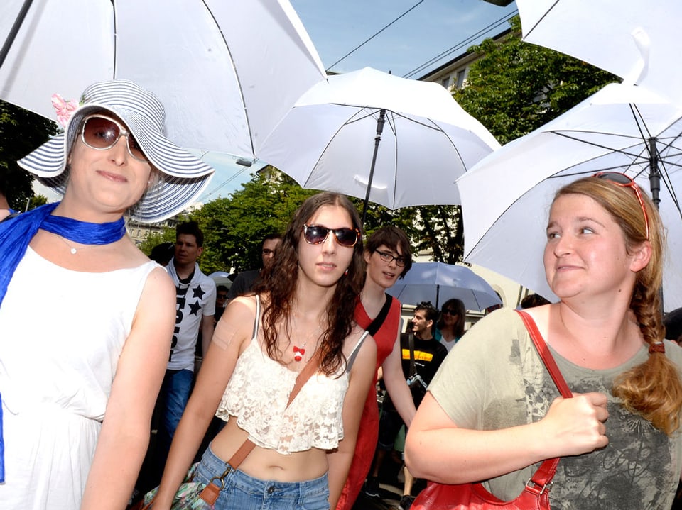 Drei Frauen unter weissen Schirmen.