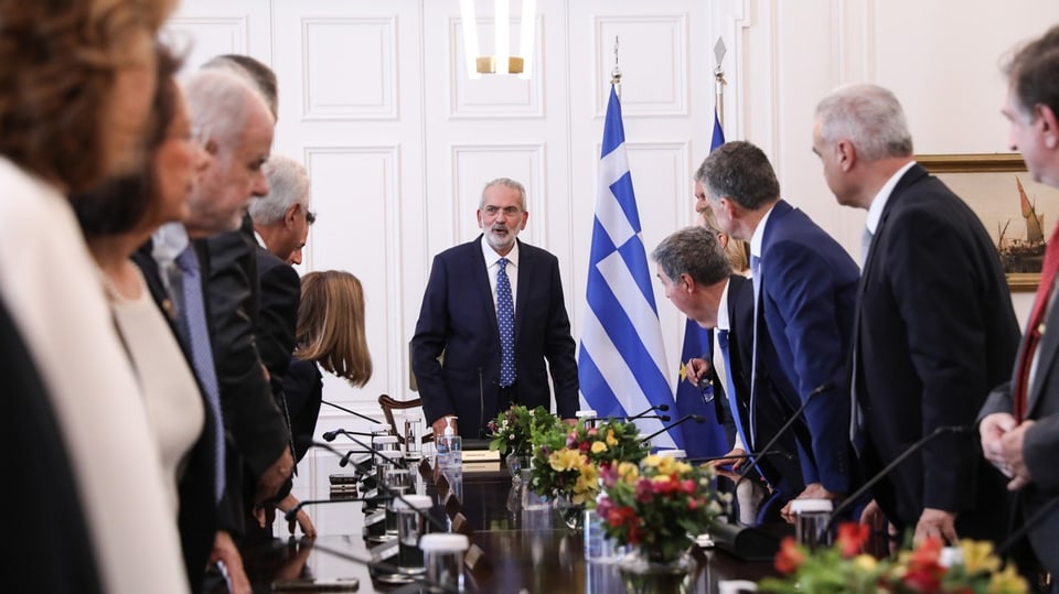 Ioannis Sarmas spricht an einem langen Tisch mit Ministerinnen und Ministern.