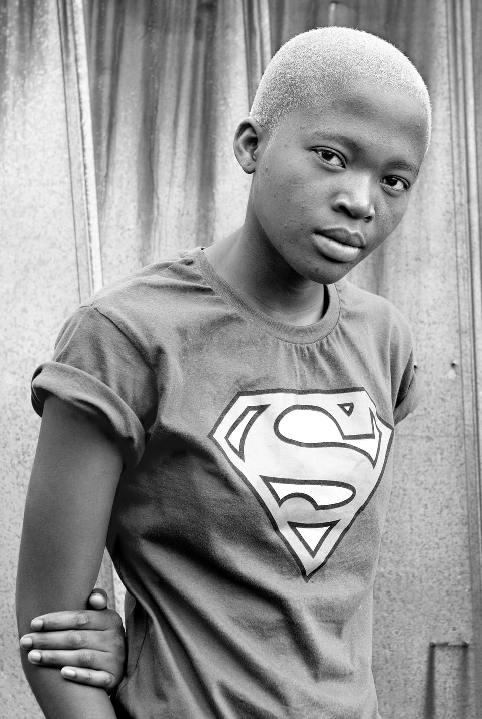 Schwarz-Weiss-Porträt einer schwarzen Frau mit blondierten Haaren und Superman-T-Shirt