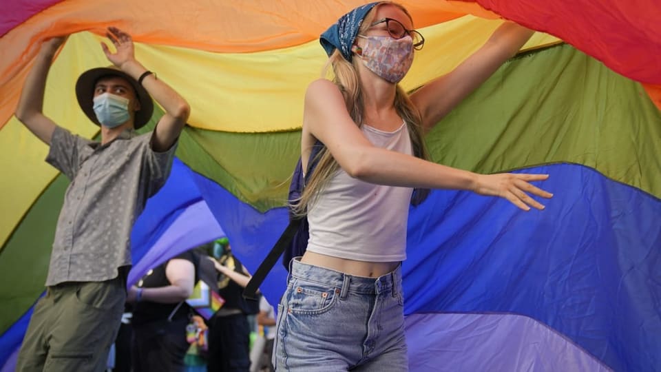 Zwei Junge Personen unter einer Regenbogenfahne