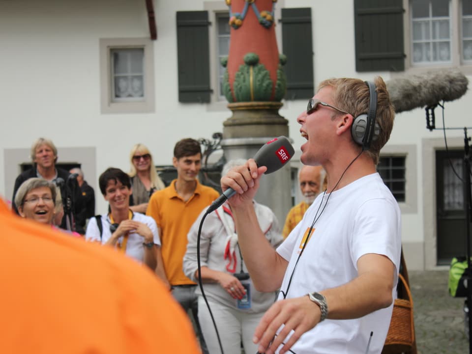 Reto Scherrer singt ins Mikrofon, die Wanderer hören zu.