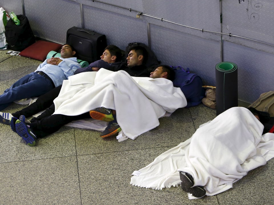 Flüchtlinge liegen eingedeckt mit Wolldecken auf dem Boden des Bahnhofs.