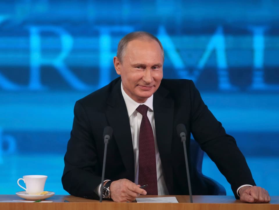 Putin lächelt zufrieden in die Kamera. 