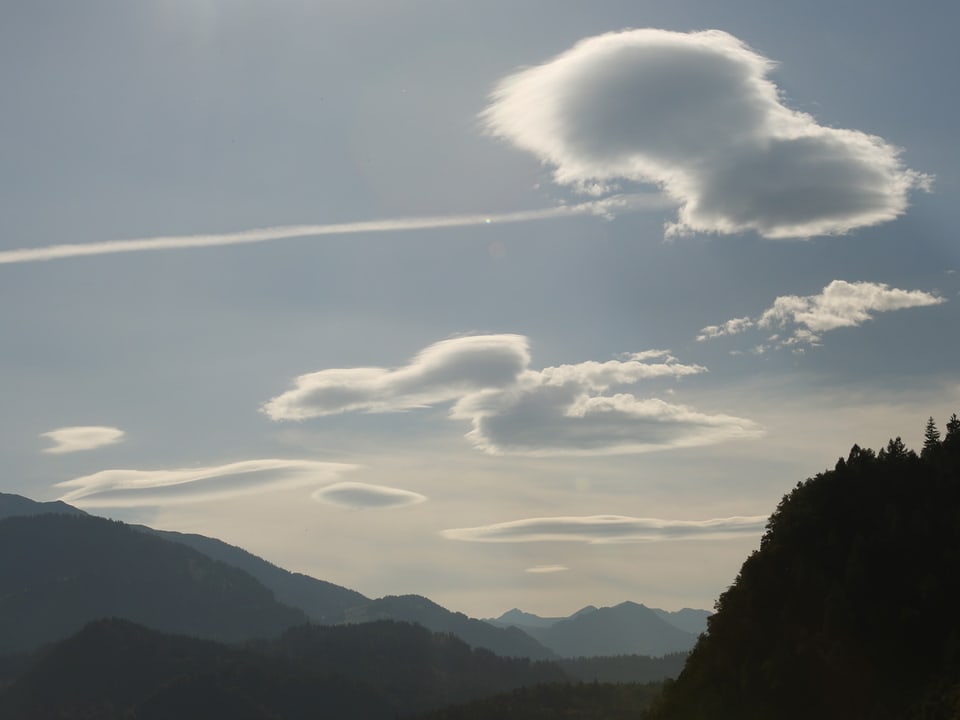 Mit Blick in die Surselva sieht man linsenförmige Wolken stationär am Himmel stehen.
