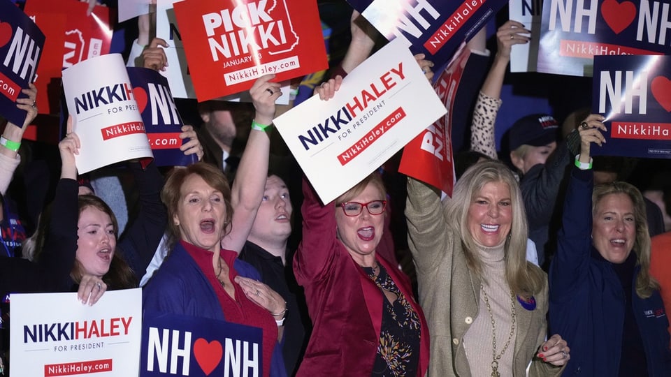 Menschen, hauptsächlich Frauen, halten Nikki-Haley-Plakate hoch und rufen.