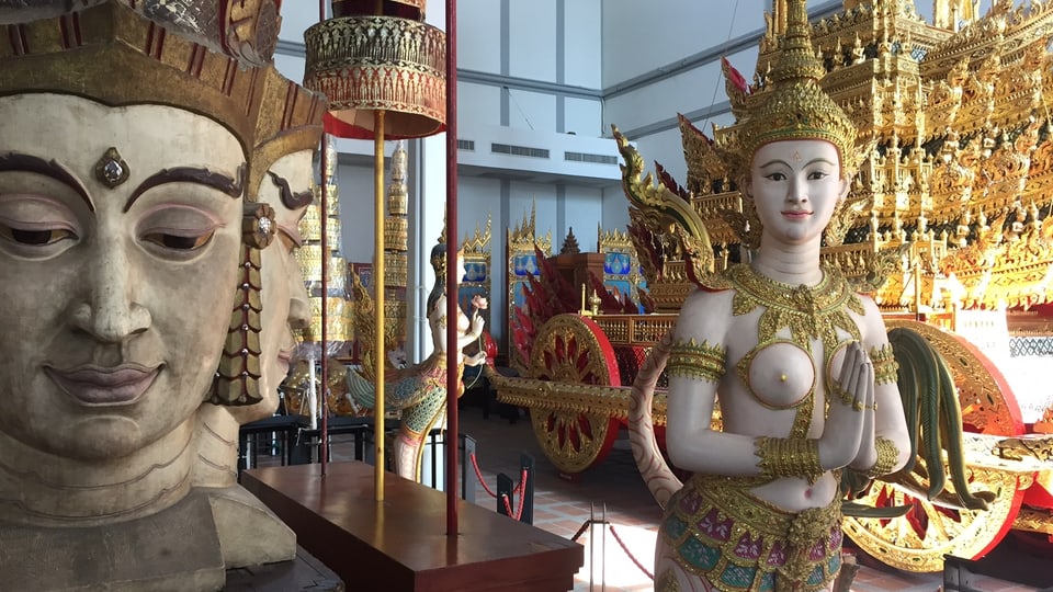 Thailändische Gottheits-Figuren und der goldene Wagen im Hintergrund.