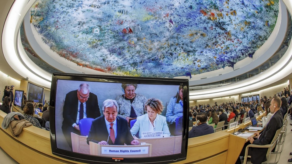 Shot from the Palais des Nations with a screen showing Guterres, among others