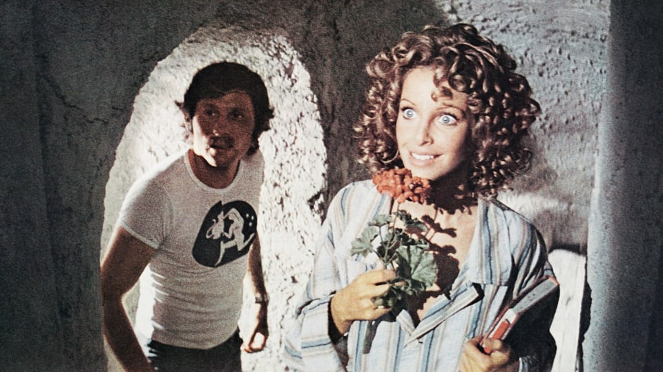Filmstill aus den 70er-Jahren mit dem Regisseur Roman Polanski und der Schauspielerin mit einer Blume in der Hand.