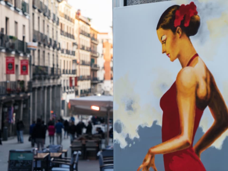 Gemälde einer Frau daneben die Strasse einer grösseren Stadt.
