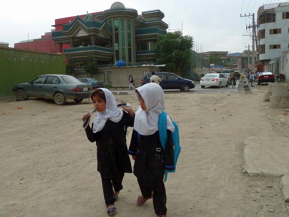 Mintgrüner Palast im Armenviertel Kabuls. Im Vordergrund sind zwei Mädchen mit Kopfbedeckung zu sehen.