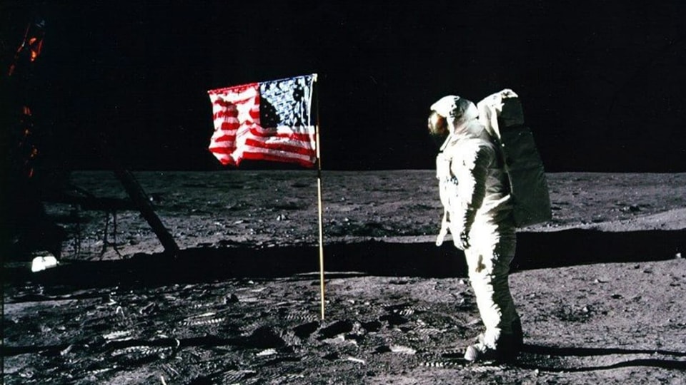 Astronaut auf dem Mond neben der US-Flagge.