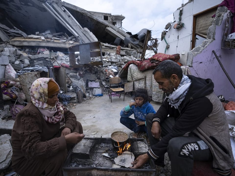 Mitglieder der Familie Al-Rabaya essen vor ihrem zerstörten Haus in Rafah.