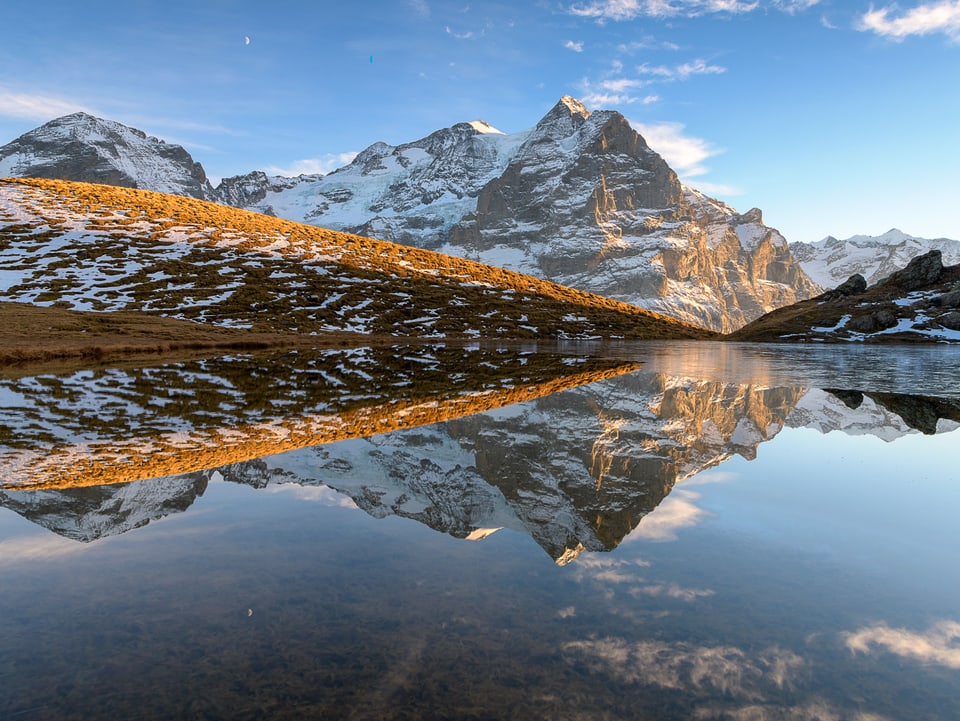 Blick auf einen spiegelglatten Bergsee.