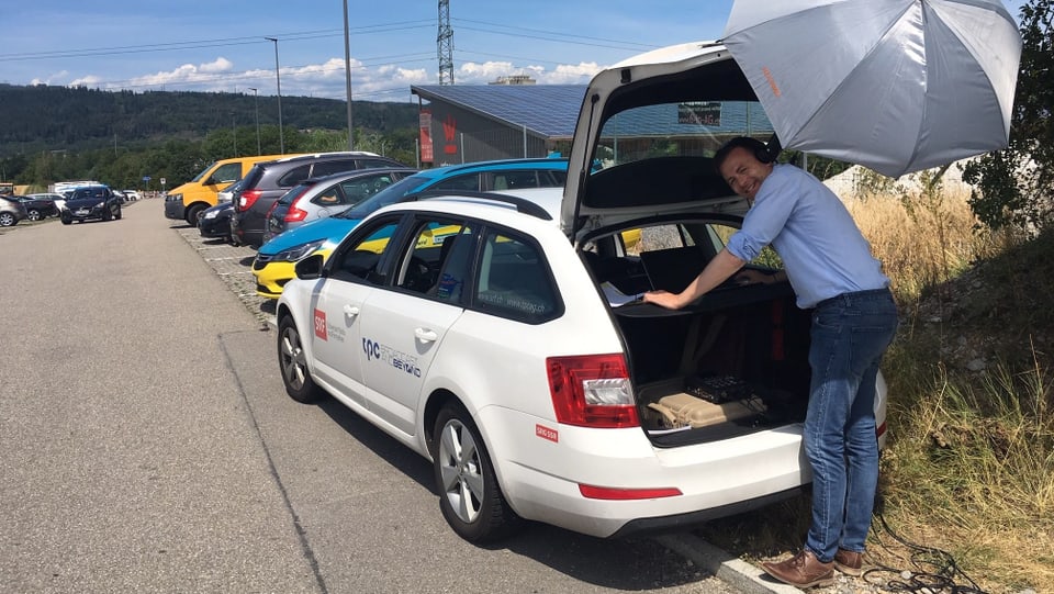 Mann steht bei offenem Kofferraum von Auto.