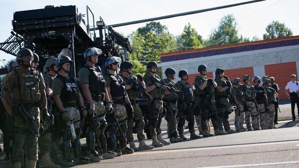 Polizisten in voller Kampfmontur vor einem Spezialfahrzeug.