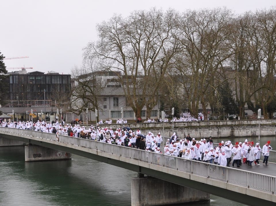 Viele Kinder in weissen Nachthemden und mit weissen Zipfelmütze marschieren über eine Brücke in Solothurn