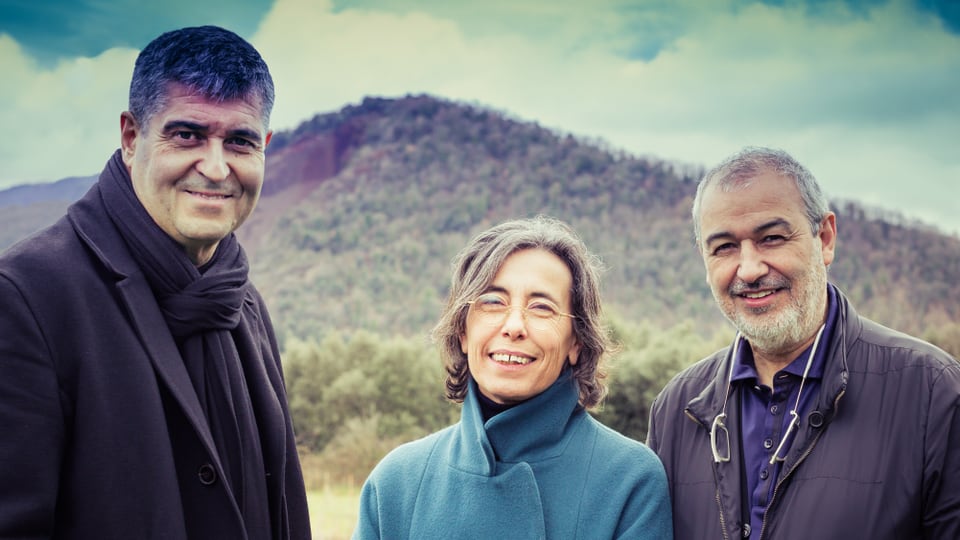 Architekten Rafael Aranda, Carme Pigem und Ramon Vilalta stehen vor einer grünen Landschaft.