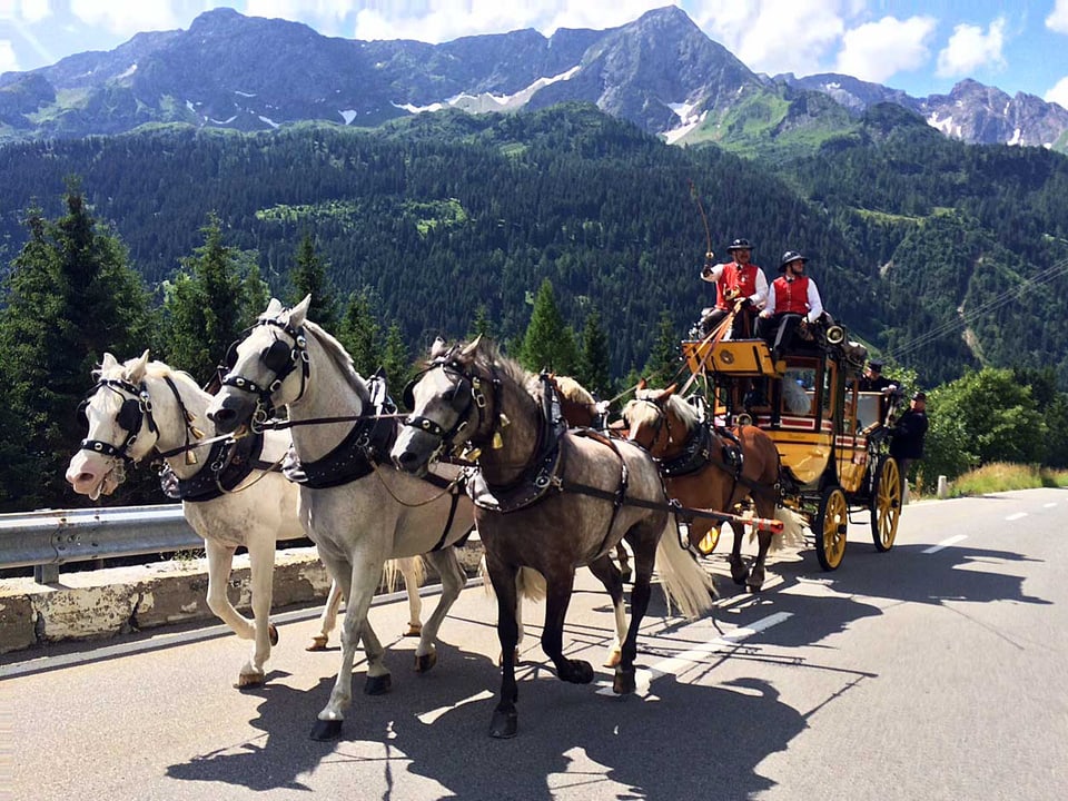 Die Postkutsche mit den Pferden, im Hintergrund das Alpenpanorama.