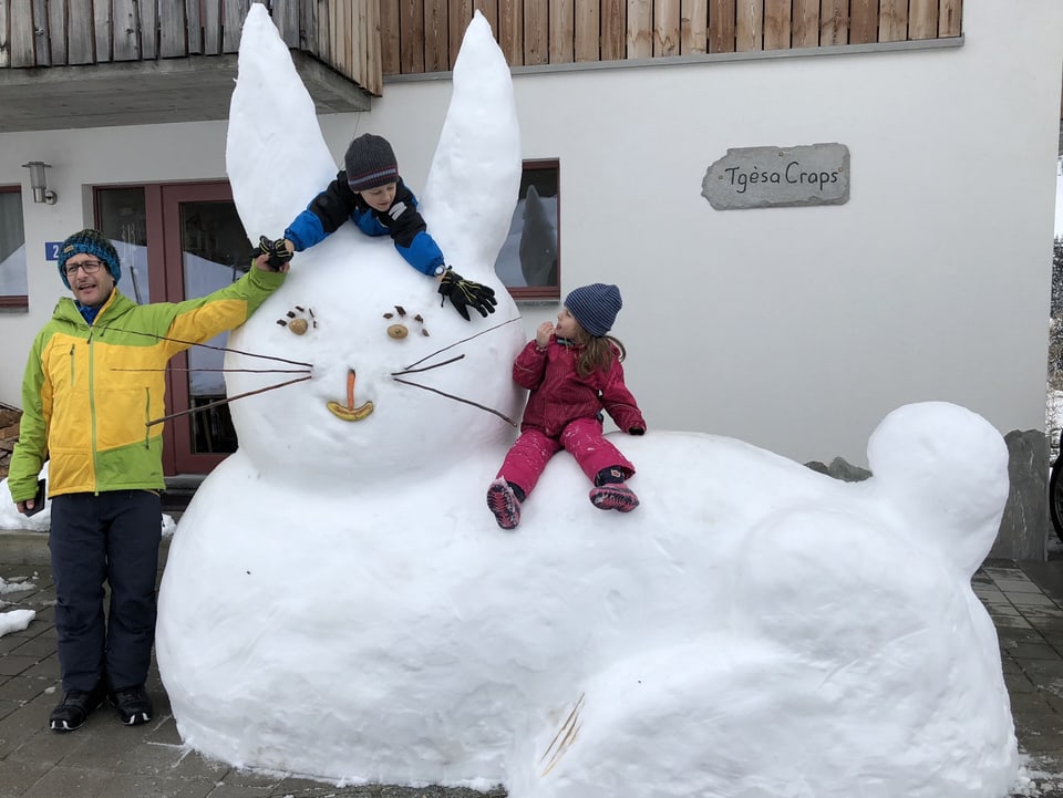 Ein über zwei Meter grosser Schneehase, auf dem zwei Kinder sitzen.