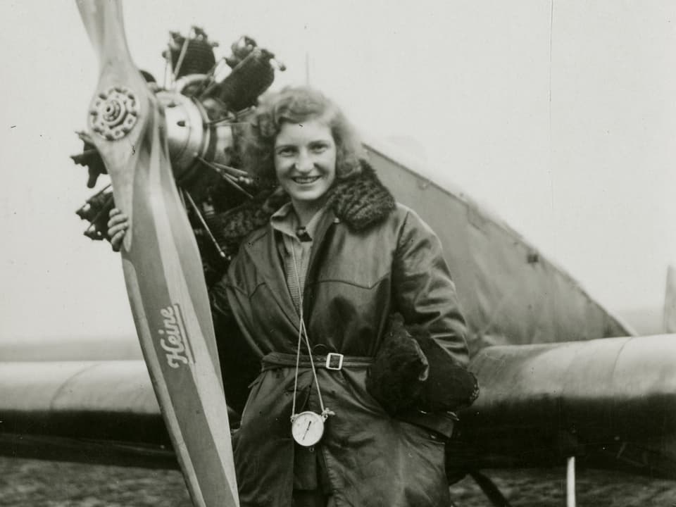 Margaret Fusbahn posiert vor einem Flugzeug, den Propeller im Arm. 