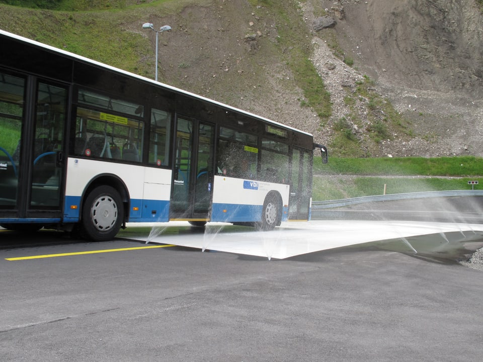 Ein Bus der vbl fährt auf die nasse Testfahrbahn zu.