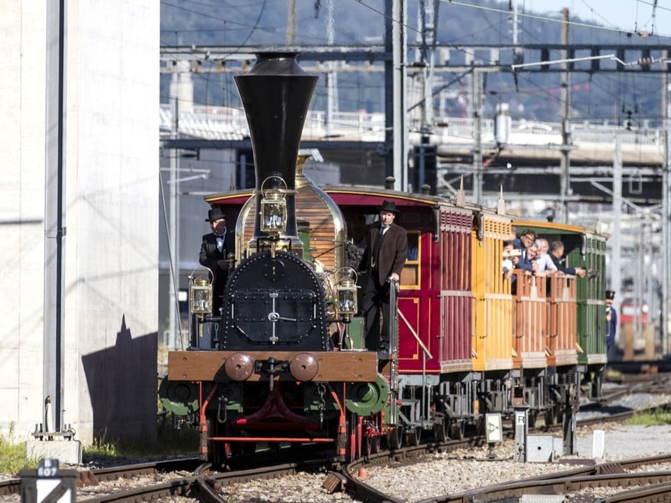 Der historische Zug mit der Dampflokomotive fährt auf dem Gleisfeld beim Zürich HB.