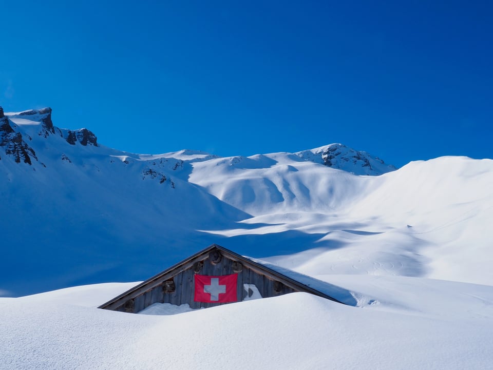Eine Alphütte im tiefen Schnee.