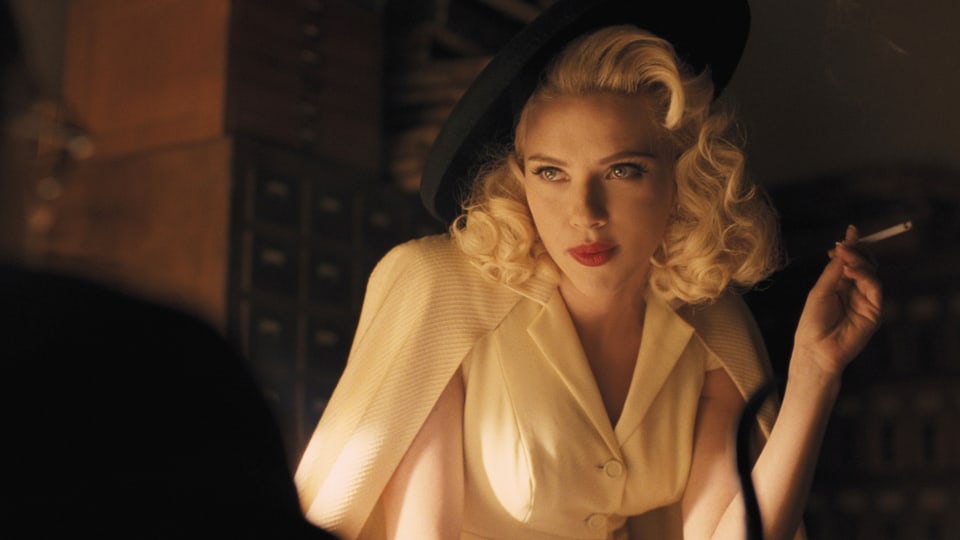 Scarlett Johansson im Stil von Marilyn Monroe mit blonden Locken, Hut und Zigarette.