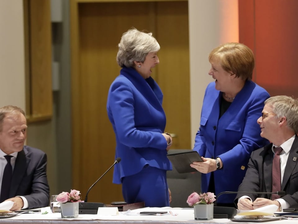 Angela Merkel und Theresa May lachen zusammen. 