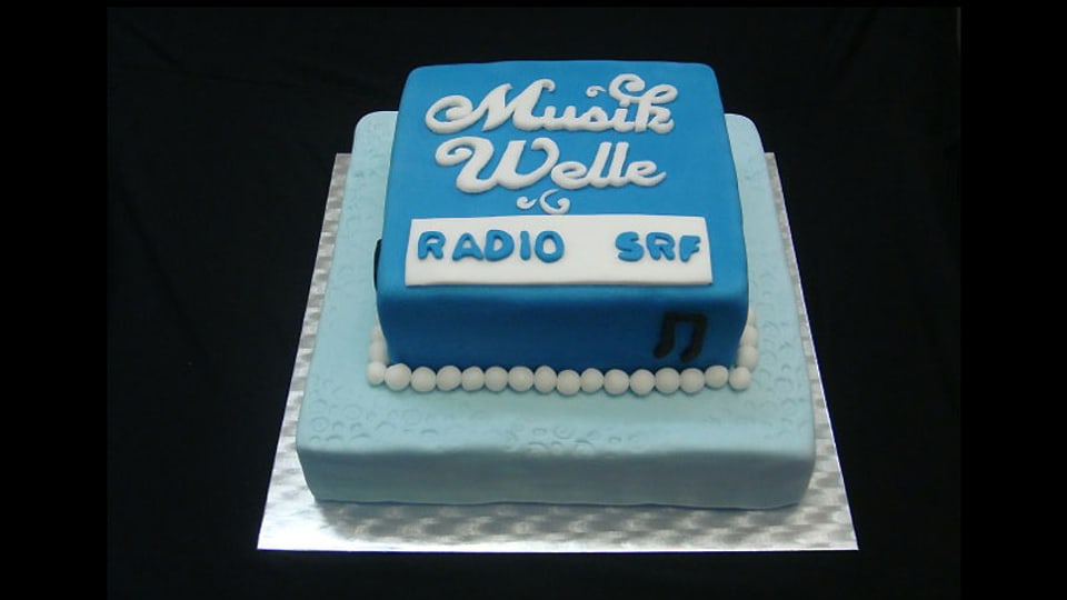Weisse Schrift auf blauem Grund: Das Logo von SRF Musikwelle auf einer zweistöckigen Torte.