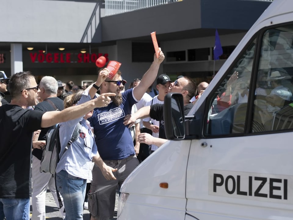 Polizeiauto und Demonstranten davor