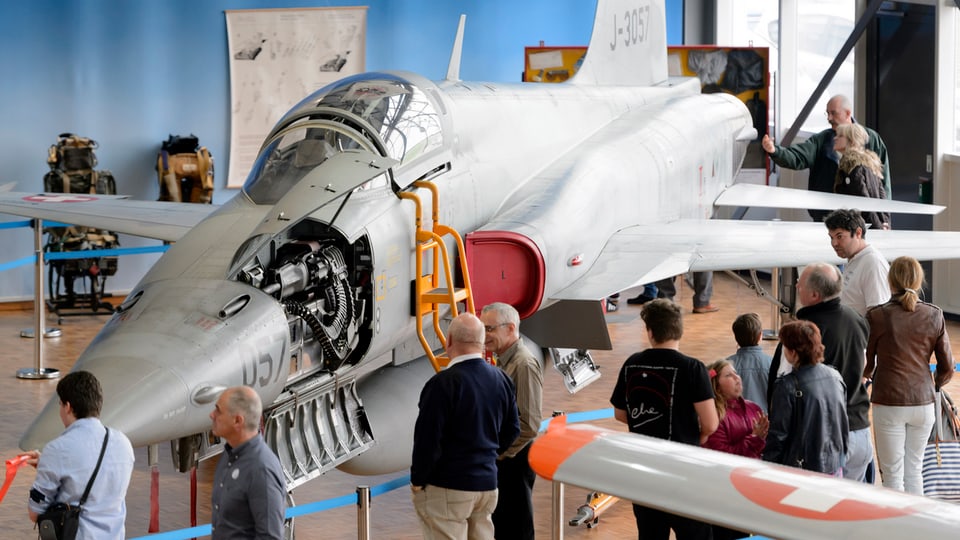 Besucher im Militärflugzeugmuseum Payerne betrachten einen ausgemusterten Tiger F5 Kampfjet