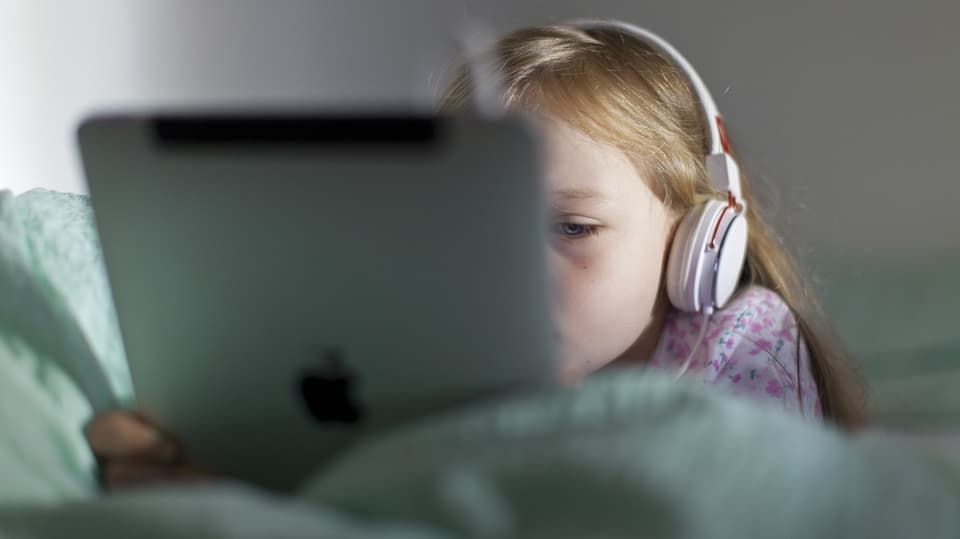 Mädchen hört mit Kopfhörer und iPad Musik.