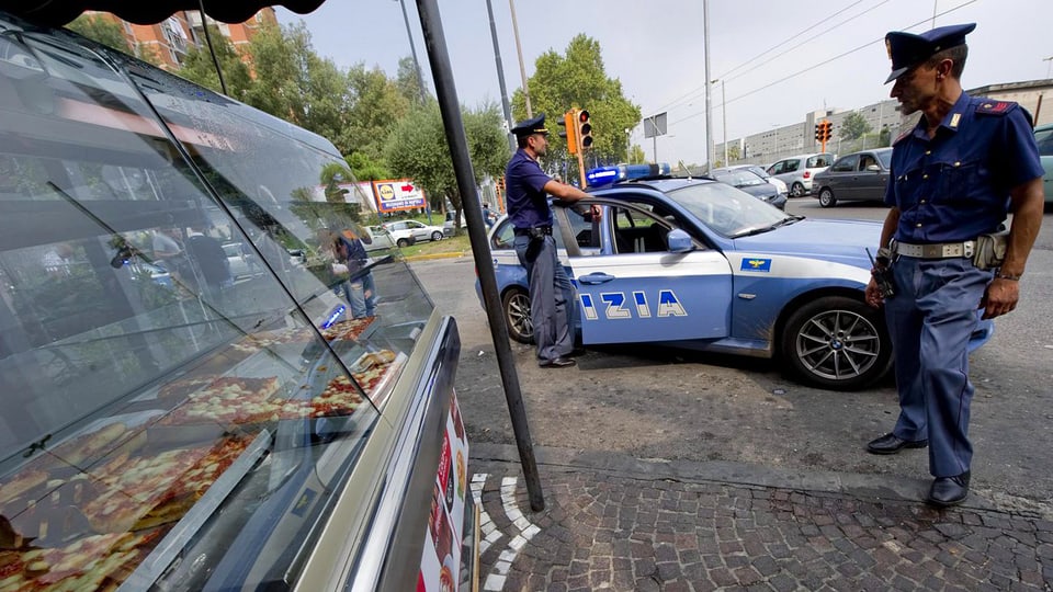Zwei Polizisten stehen vor einem Polizeiauto auf der Strasse in Neapel.