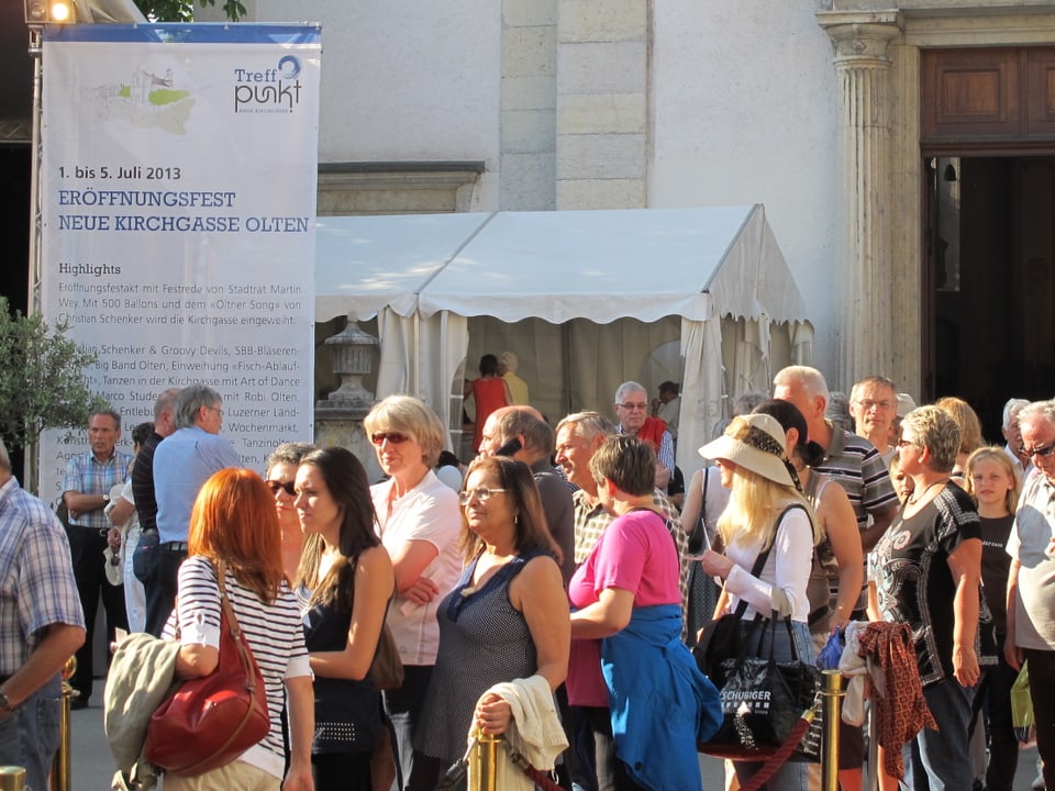 Gut ein Dutzend Personen stehen vor der Oltner STadtkirche, dazwischen ein Plakat welches die Eröffnungsfeier ankündet und mehrere Zelte.