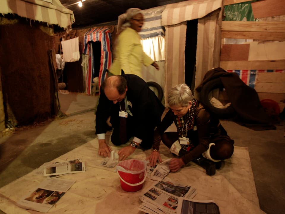 Das Ehepaar Balcke faltet Zeitungen in einem simulierten Ghetto.