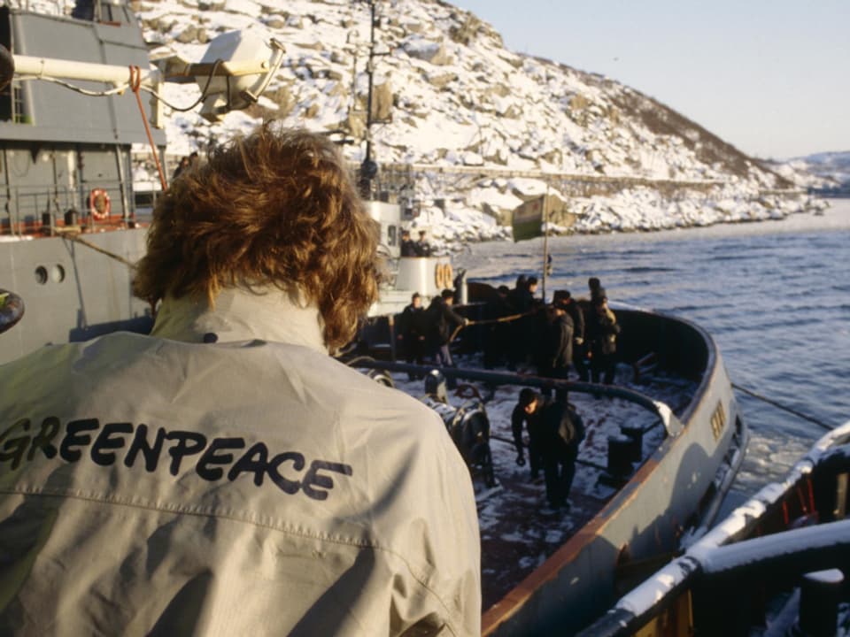 Ein Greenpeace-Aktivist betrachtet die russische Küstenwache.