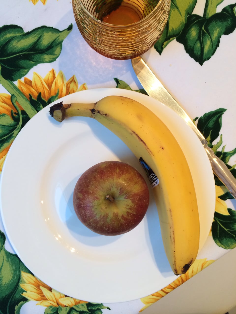 Banane und Apfel liegen auf einem Teller.