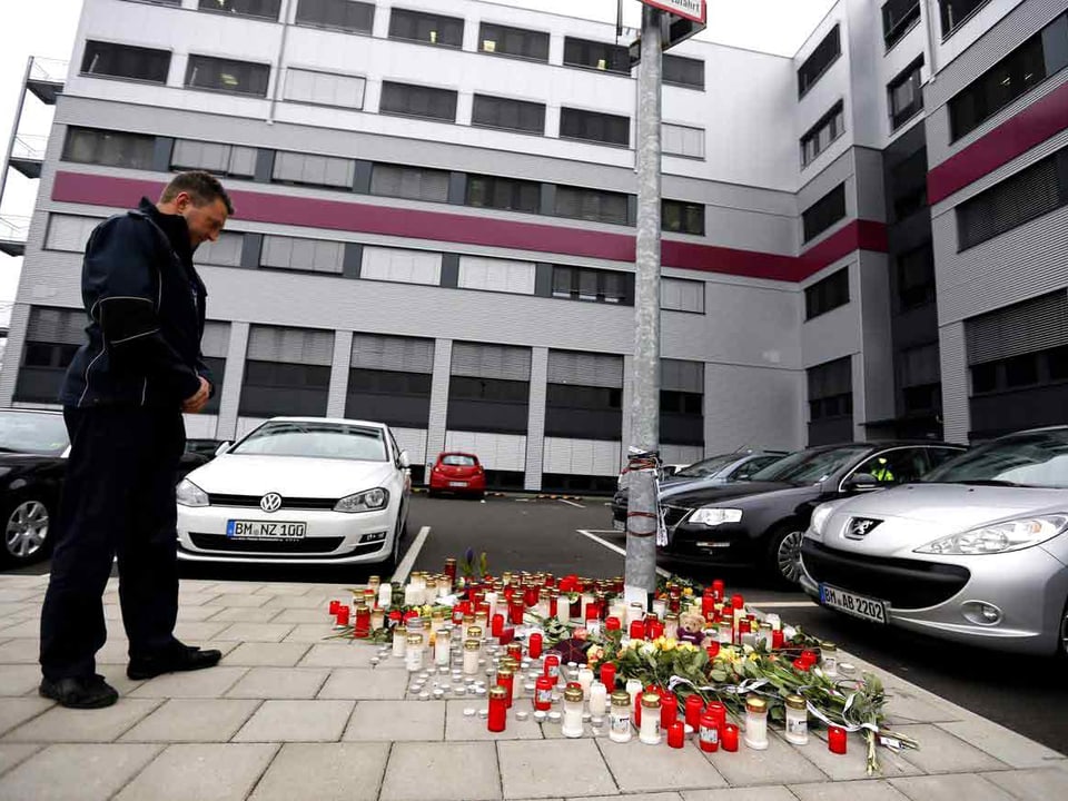 Ein Polizist steht vor den Kerzen bei der Germanwing-Zentrale.